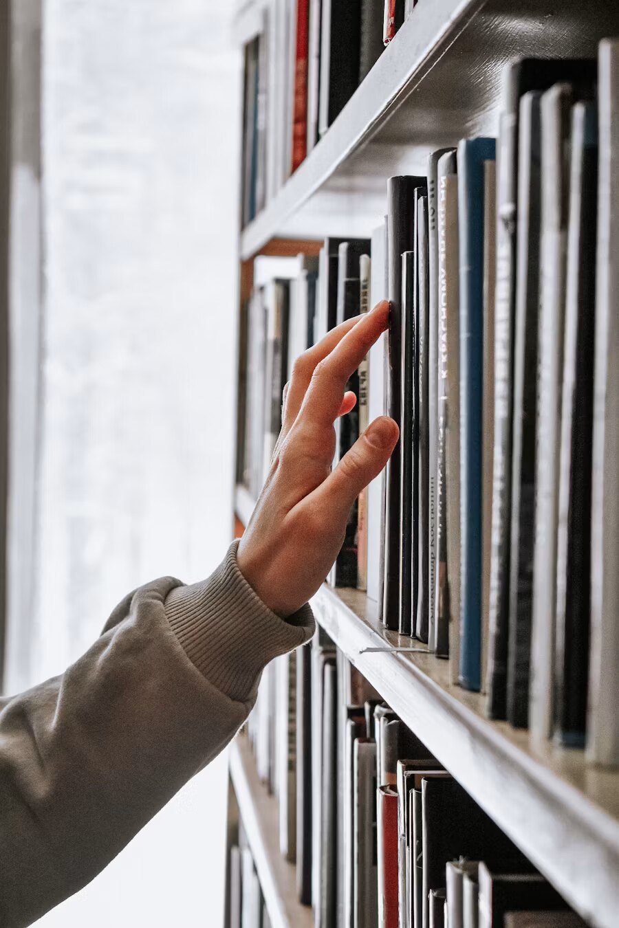 A hand reaching for a volume on the shelf
