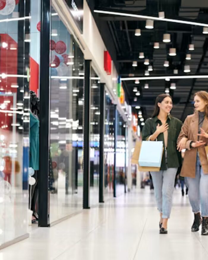 Two friends carrying Mercer and Vale shopping bags through a bright store corridor