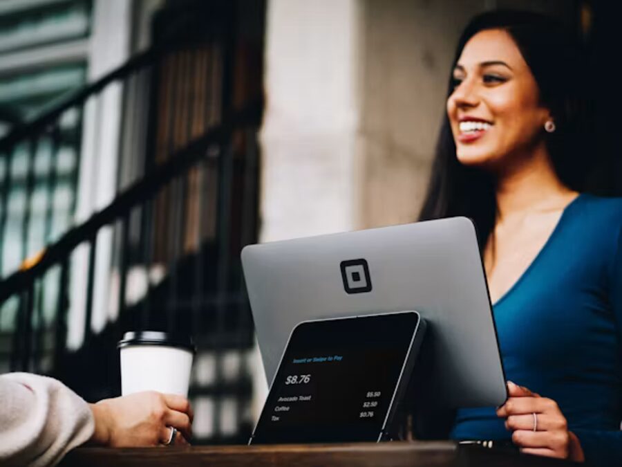 A customer paying with a card at the Mercer and Vale counter, greeted by a smiling shop assistant